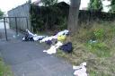 Piles of discarded clothing lies strewn across a verge in Normandy Crescent, Cowley